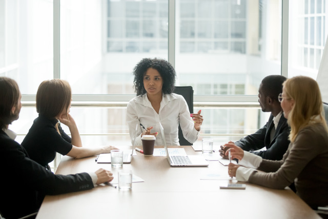 Black female boss leading corporate meeting talking to diverse b