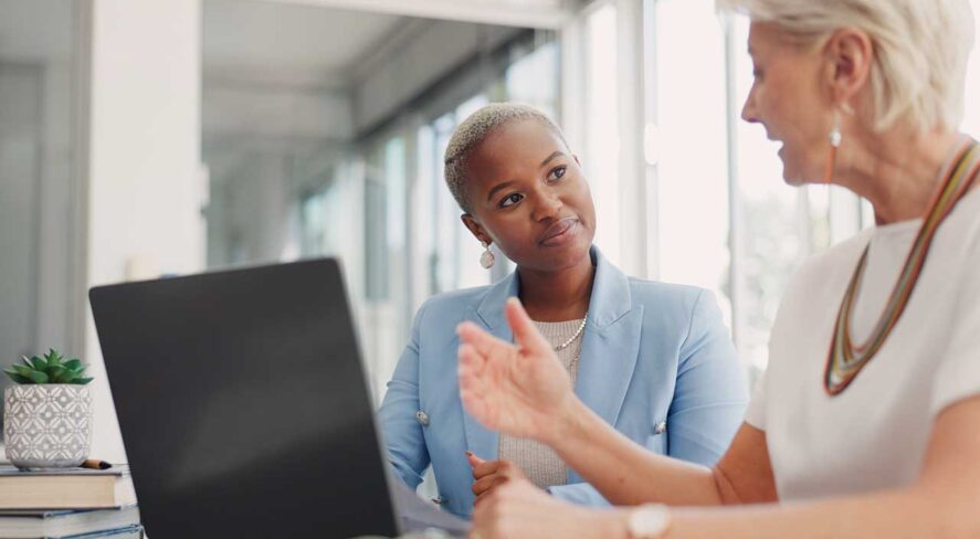 women sitting at computer and talking